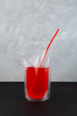 Red adult alcoholic drink in spill-proof reusable drink pouch. Fruit berry fermenting lemonade. Wine slushy in plastic bag. Convenient format for party and picnics. Take away drink