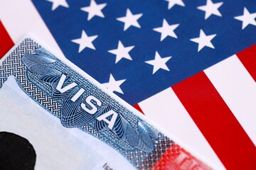 U.S. VISA United States of America. American Tourist or Green Card Visa on flag background close up