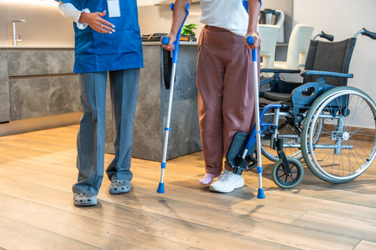 Nurse assisting patient with crutches during physiotherapy rehabilitation