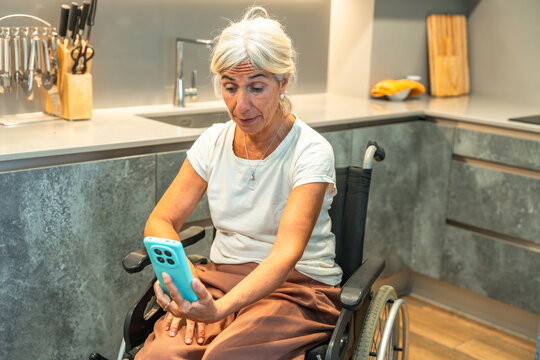 Senior woman in wheelchair having video call at home