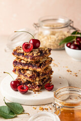 Stack of baked oatmeal crumble squares with fresh cherry. Cherry oatmeal crumble bars. Quick and easy homemade red berry pie with streusel. Crumble fruit cake. Home cooking.