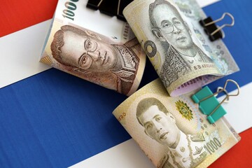 Thai baht currency money bills lies on flag close up. The concept of business and investment