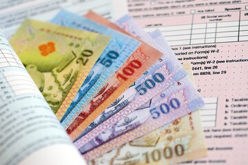 Thai baht money bills on tax form close up. Taxation and accounting concept