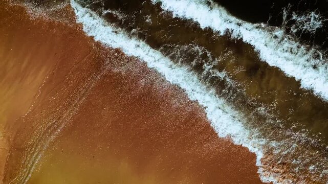 Shallow wave touching golden sandy beach. Sea foam sparkling on smooth wet shore. Ocean water gliding across bright coastline. Surf blending with soft sand in gentle motion