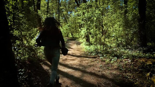Horrified woman running away and looking back in fear from serial killer. Panicked female fleeing through forest and glancing behind at maniac. Terrified lady escaping and turning around in shock from