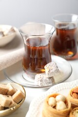 Traditional Turkish tea, brown sugar and sweets on white table, closeup