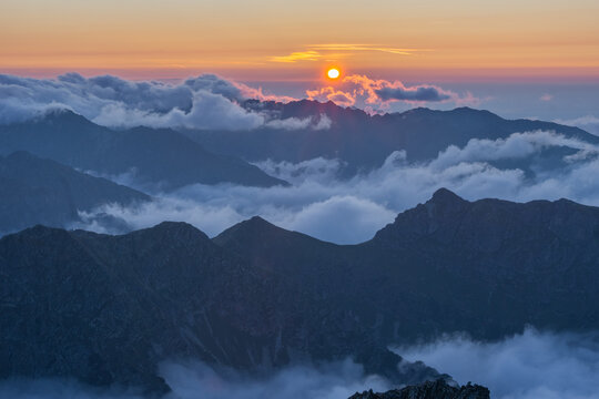 Aerial view of mist-shrouded peaks of Maly Ladovy stit pierce through the clouds as the sun casts a warm glow, Tatranska Javorina, Presov Region, Slovakia.