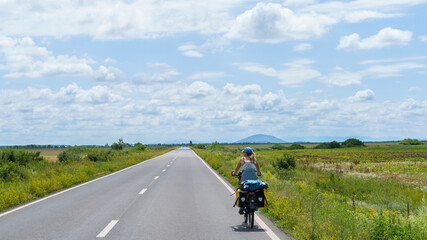 Obraz premium Woman Cycling on Straight Road in Great Hungarian Plain, Hungary