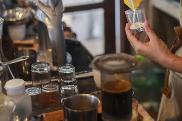 Professional barista making coffee by pouring milk into glass. An artisanal drink preparation in...