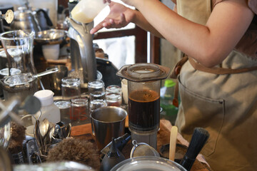 Professional barista with focused concentration making and brewing coffee. barista carefully pour hot water through filter in cozy cafe shop to prepare fresh drink