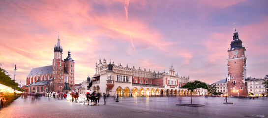 Panorama of St Mary's Basilica (Mariacki Church) and The Main Market and tower in the Old Town of Krakow, Poland illuminated at sunset
