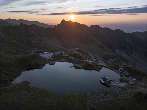 Aerial view of the serene B&acirc;lea Lake reflecting the fiery sunset amidst the rugged peaks of the Făgăraș Mountains, Romania., Bucharest, Romania.
