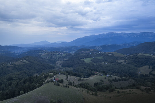 Aerial view of a vast expanse of rolling hills and distant mountains under an overcast sky, Bucharest, Romania.