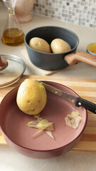 Anonymous peel boiled potatoes with knife in the kitchen. High-quality farm products.