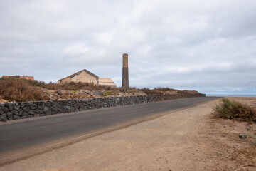 Solitary road crossing through the rugged northern coast of the island with the ocean to the right and ruins of an old sugar processing factory to the left, Los Silos, Tenerife, Canary Islands, Spain