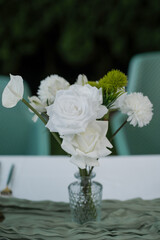 Centerpiece featuring fresh white roses, carnations, chrysanthemums and anthurium, accented with a touch of green foliage, beautiful arrangement as a table decoration for a wedding or a special event