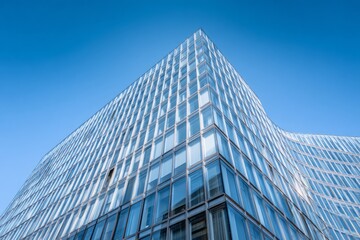 Fototapeta premium Modern glass facade building curves against clear blue sky.