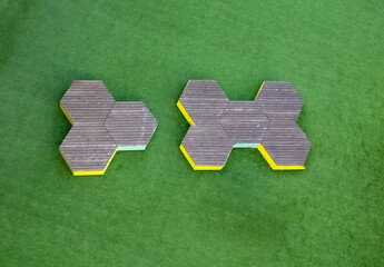 Aerial view of two tessellated geometric forms, their yellow edges stark against the lush green backdrop, creating a mesmerizing contrast, Nahariyya, North District, Israel.