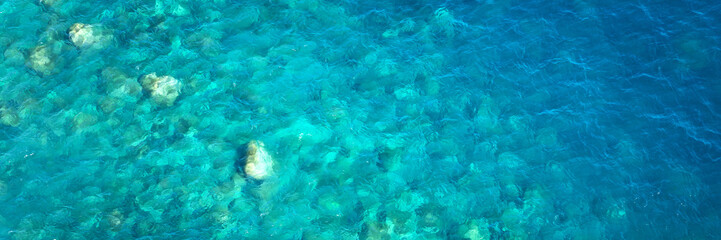 Drone view of rocks and blue pristine sea with clear transparent water. Ocean panoramic background with copy space