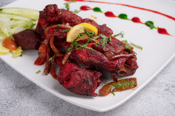 Chicken Tikka Masala Wings – Spicy grilled chicken wings marinated in rich tikka masala seasoning, served with fresh cucumber salad and colorful sauce garnish on a modern white plate, Indian food