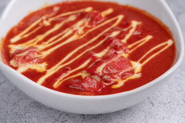 Chicken Tikka Masala Curry - Classic Indian dish with tender grilled chicken pieces simmered in a rich spiced tomato and cream sauce, garnished with cream swirls, served in a white bowl on stone