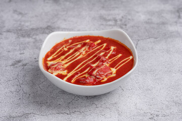 Chicken Tikka Masala Curry - Classic Indian dish with tender grilled chicken pieces simmered in a rich spiced tomato and cream sauce, garnished with cream swirls, served in a white bowl on stone