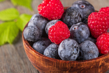 Stunning macro photography of raspberries and blueberries in wooden bowl