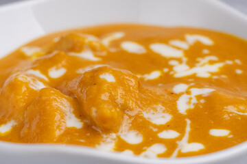 Butter Chicken Curry Creamy and rich North Indian curry featuring tender chicken pieces in a velvety tomato and butter sauce, topped with a swirl of cream, served in a white bowl