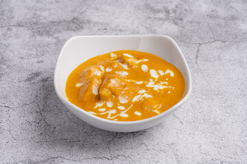 Butter Chicken Curry Creamy and rich North Indian curry featuring tender chicken pieces in a velvety tomato and butter sauce, topped with a swirl of cream, served in a white bowl