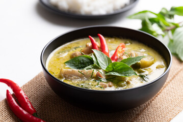 Thai green curry chicken in black bowl with rice and ingredients