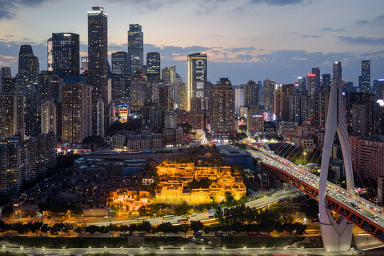 Aerial view of a mesmerizing Chongqing skyline at night, where the Hongyadong glows like a golden hive and the Qiansimen Bridge streaks with red tail lights, Chongqing, China.