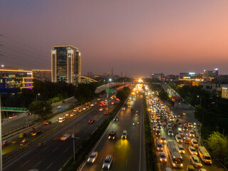 Aerial view of cityscapes blend into the horizon, with traffic flowing like arteries of light against the urban backdrop at DLF Cyber City, Gurugram, Haryana, India.