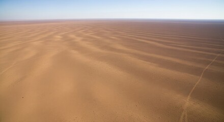 Naklejka premium Expansive desert landscape with rippled sand patterns under clear sky