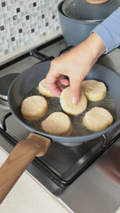 Anonymous person fries potato croquettes in vegetable oil in new, trendy frying pan. Farm produce. Home cooking. Traditional cuisine.