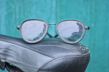 one black sunglasses lies on the seat of a sports bike on a summer city street the green wall