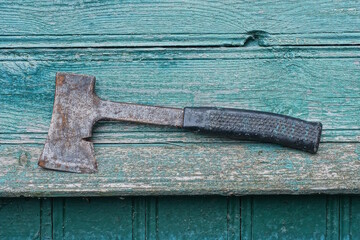one old black gray axe lies on a green wooden table