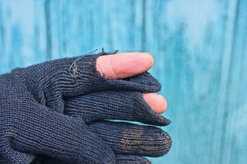 part of an old black dirty torn cloth glove with fingers in holes on a green background