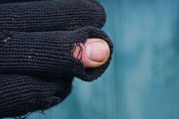 part of an old black dirty torn cloth glove with fingers in holes on a green background