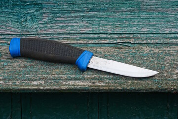 one knife with a black blue plastic handle lies on a green wooden table