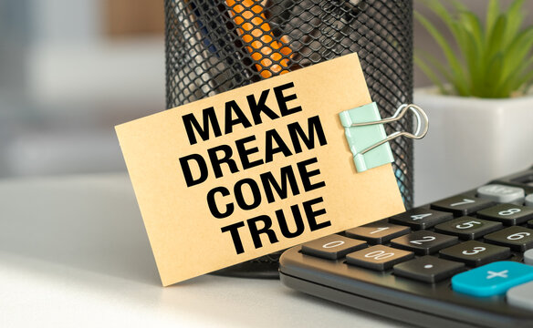 A small piece of paper with the words Make Dream Come True written on it is clipped to a metal clip.