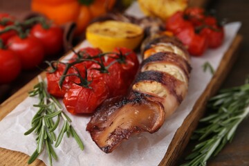 Tasty stuffed squid, rosemary and tomatoes on wooden table, closeup