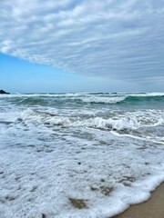 Close-up of sea foam and ocean waves on sandy beach
