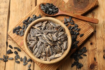 Unpeeled sunflower seeds on wooden table, flat lay