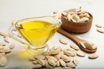 Pumpkin seeds and oil on white table, closeup