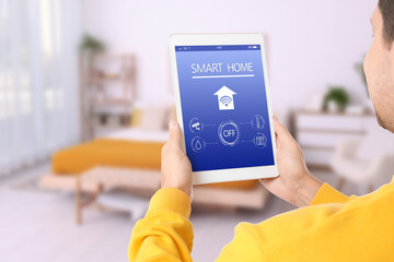 Man using smart home app on tablet computer to control house features, closeup