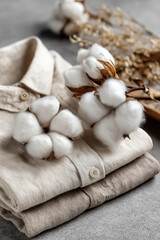 Obraz premium Soft cotton bolls placed on folded linen shirts, symbolizing natural textile materials and sustainable fashion craftsmanship