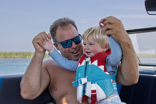 Close up of a child wearing a life jacket and playing with his father