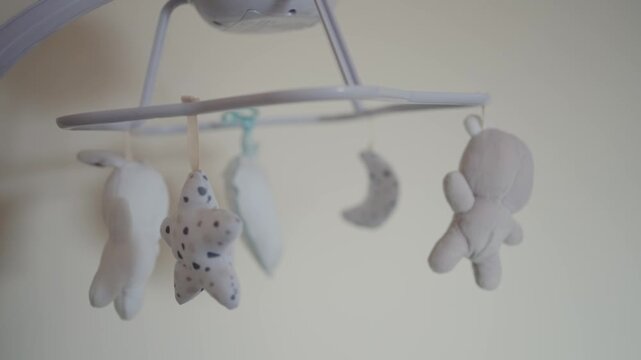 Delicate baby mobile with stuffed moon and star figures in soft focus light
