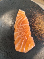 Raw salmon fillet placed on a black tile plate