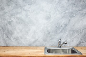 Obraz premium Clean stainless steel sink on wooden countertop against gray marble wall.